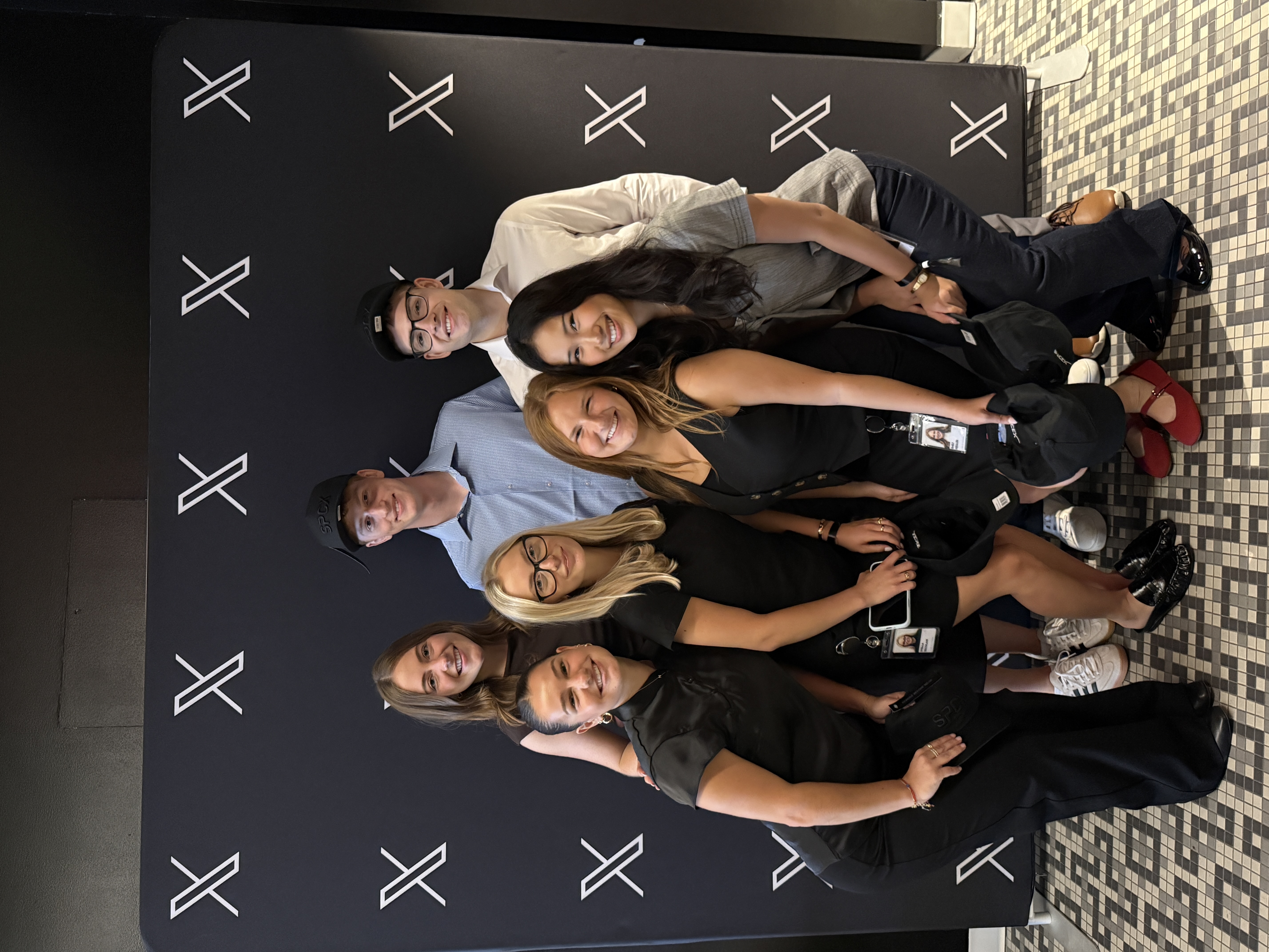 Boden with a group in front of the X logo backdrop